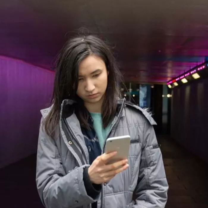 Young person looking at their phone in a tunnel
