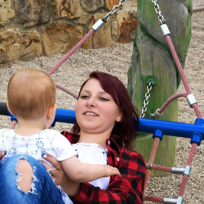 Woman holding their baby on a hammock.