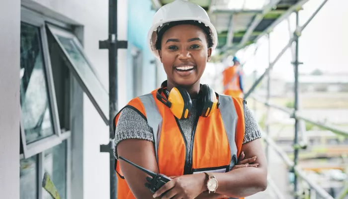 Young person smiling in high vis and hard hat on construction site