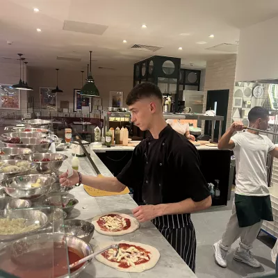 A young chef prepares pizza