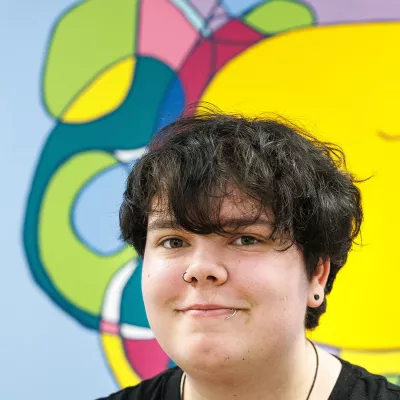 Young person in front of a colourful mural