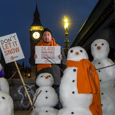 Snowmen outside the Houses of Parliament in London, with placards reading 'Don't Let It Snow'
