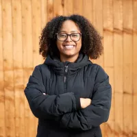 Young person stood against wooden fence 