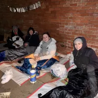 adults wrapped up on floor in sleeping bags