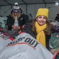 a woman sits in a sleep out branded centrepoint sleeping bag smiling at the camera