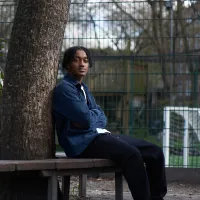 Young person sitting next to a tree