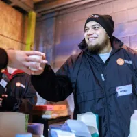 Centrepoint staff hands out a warm drink to a Sleep Out participant