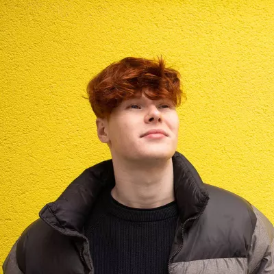 Young person in front of yellow wall, looking up