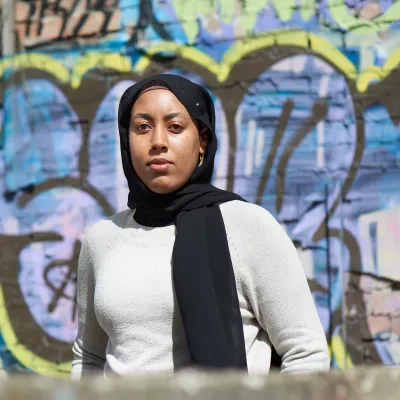Young person stood against a wall with graffiti on 