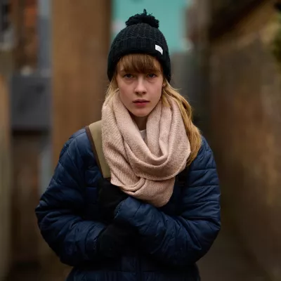 Anna, a young homeless person, stands in winter clothing in an alleyway