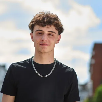 A young person stands smiling with hope in the street