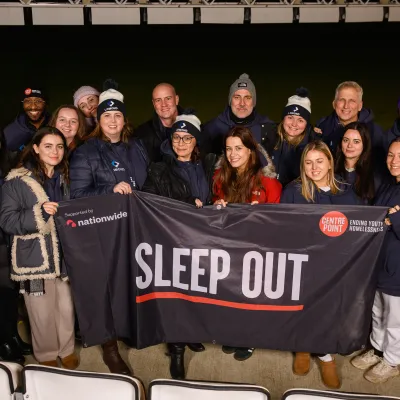 Group of Lomond staff in beanies holding a 'Sleep Out' sign