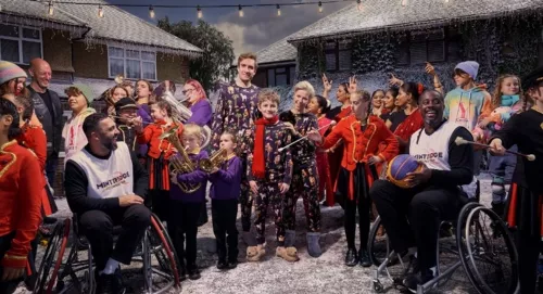 Picture taken from M&S Christmas campaign showing lots of people sat and stood around a family in a Christmas scene.