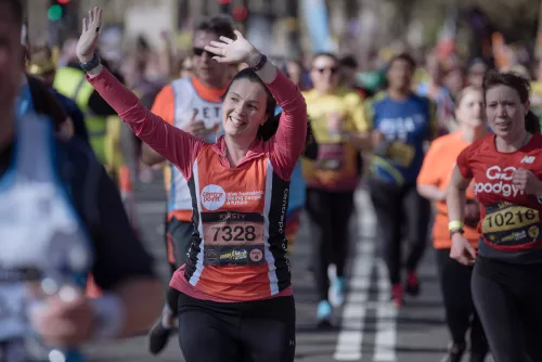 Centrepoint runner waving at crowd whilst running at an organised race.