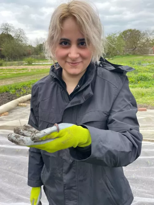 Young person outside holding a worm