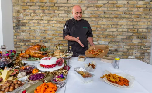 Chef Aldo Zilli presents a beautiful spread of food, including turkey, pigs in blankets, cake, sweets, carrots, mince pies, and contrasts with takeaways to show the difference for homeless people at Christmas.