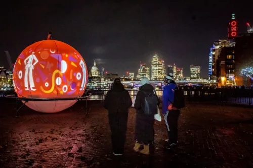 Londoners watch the snow globe art installation lit up on the Southbank at night