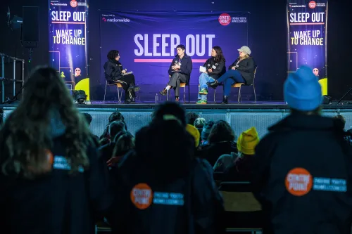 people sit and listen to a panel discussion at sleep out