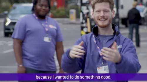 Two young men fundraise for Centrepoint on the street, wearing purple Centrepoint-brainded tshirts and jackets.