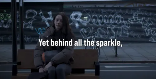 "Yet behind all the sparkle..." a young person experiencing homelessness sits on a bench