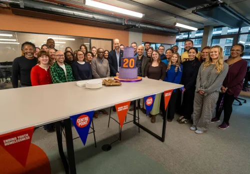HRH Prince William, Centrepoint staff and young people stand with the celebration cake at head office