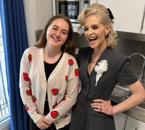 Kelly Osbourne and Ellie, a young person living at Reuben House, smile for the camera in her kitchen