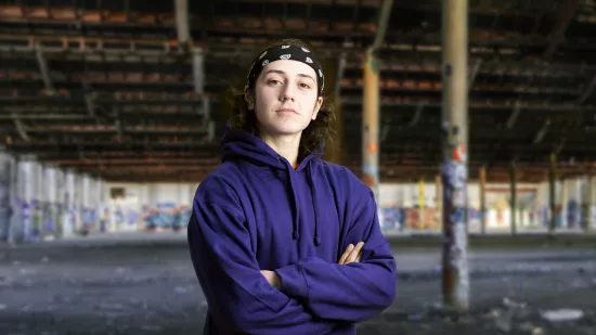 Young person in blue hoodie with arms crossed