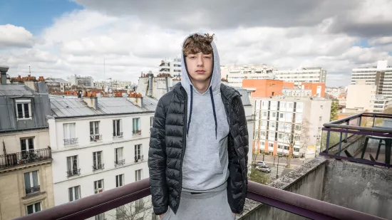 Young person on balcony overlooking cityscape