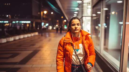 Young person in orange jacket walking outside at night