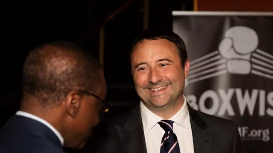 Nick wears a smart suit and chats at an event with the BoxWise banner in the background