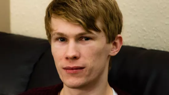 A young man sits on a sofa