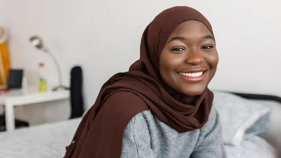 Young women smiling on her bed in her Centrepoint Room.