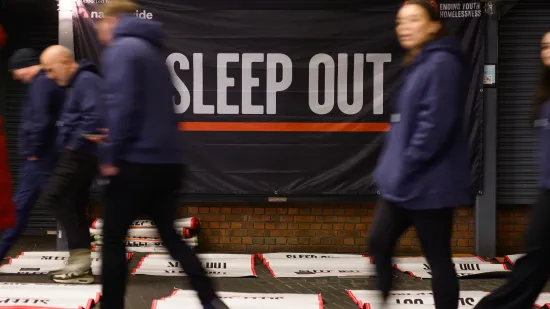 people walking past a Sleep Out poster