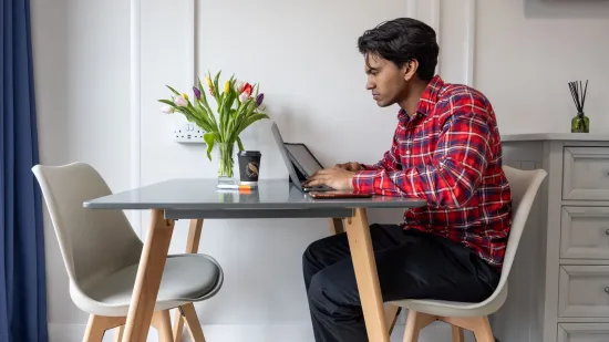 Young person sits at his desk on a computer