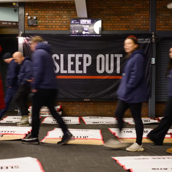people walking past a Sleep Out poster