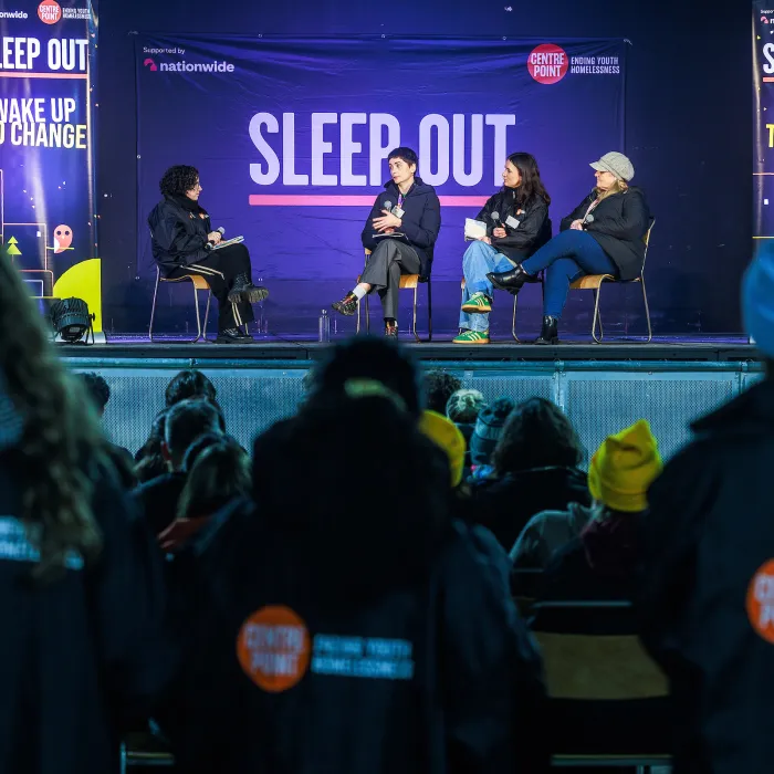 people sit and listen to a panel discussion at sleep out