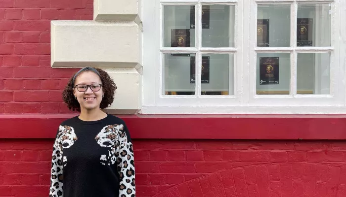 Young person standing in front of a red wall and window