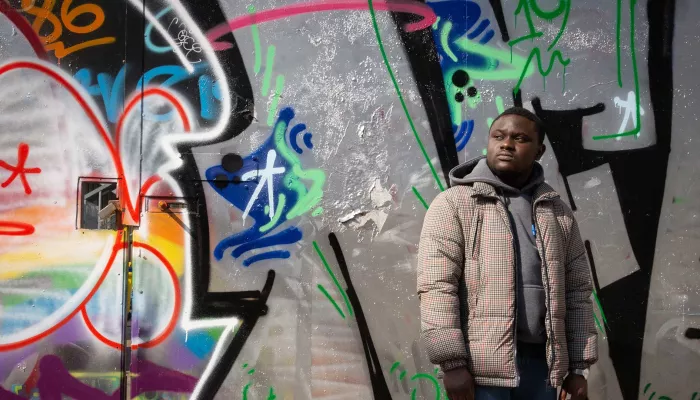 Young person standing against a wall of graffiti 