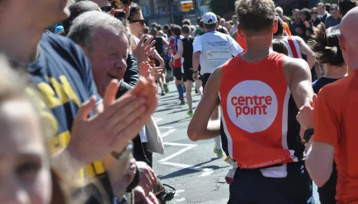 Person running at an organised running event surrounded by clapping onlookers.
