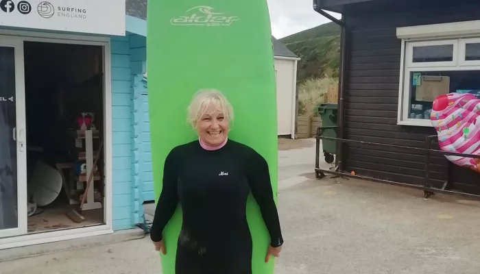 Person in wetsuit carrying surfboard