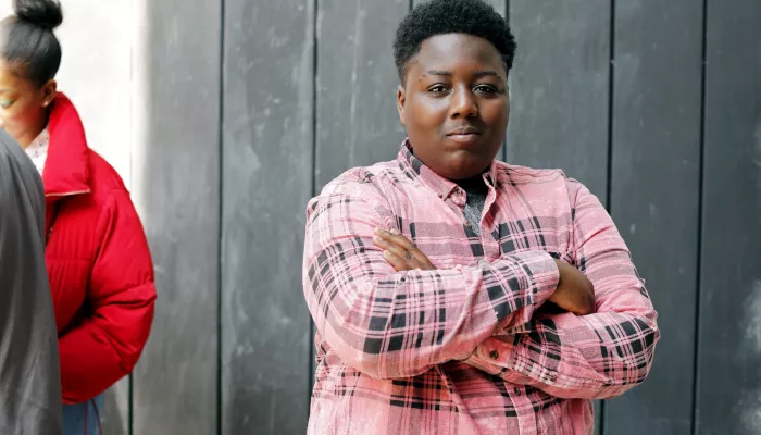 Young person in front of fence with arms crossed