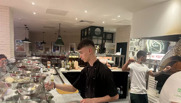 A young chef prepares pizza