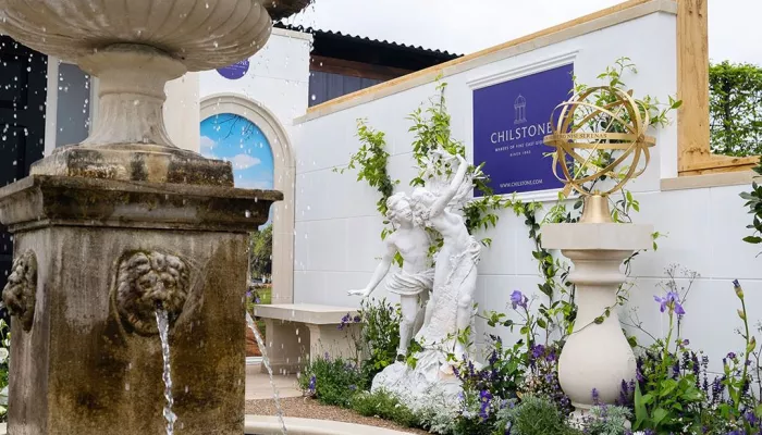 Photograph of a water fountain and statues at the Chelsea Flower Show with the Chilstone logo on a wall.