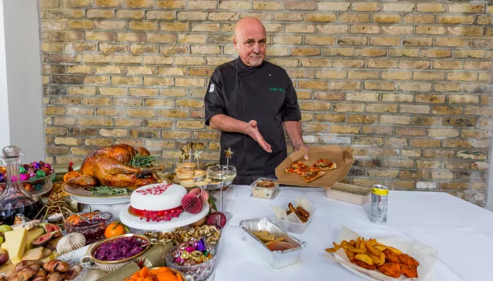 Chef Aldo Zilli presents a beautiful spread of food, including turkey, pigs in blankets, cake, sweets, carrots, mince pies, and contrasts with takeaways to show the difference for homeless people at Christmas.