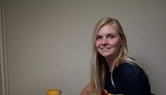 Young person with long blond hair looking into the camera and smiling