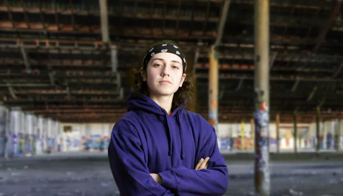 Young person in blue hoodie with arms crossed