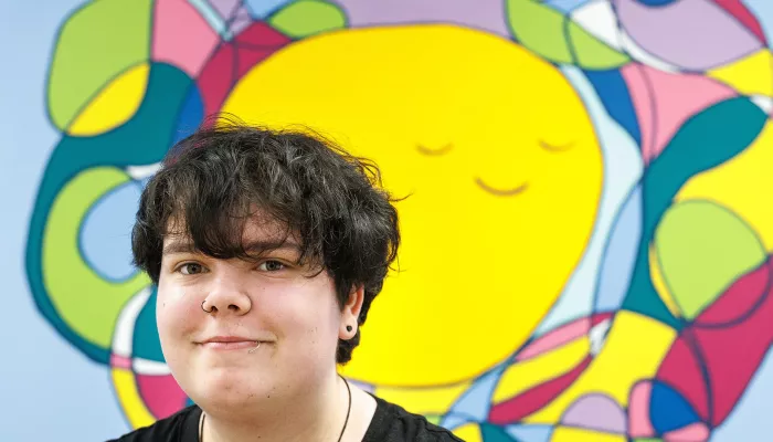 Young person in front of a colourful mural