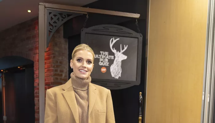 Lady Kitty Spencer smiles and stands in front of the Centrepoint logo in a pub.