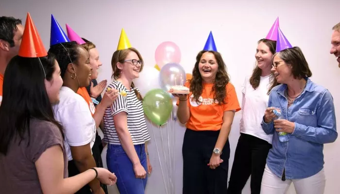 People wearing party hats, someone holding a cake