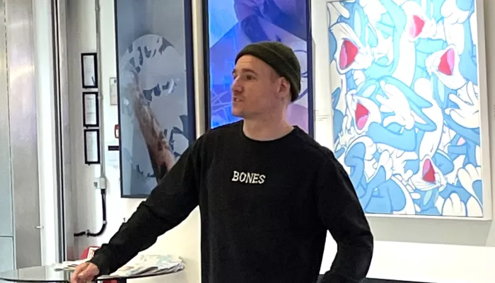 Opake stands in front of artwork at his new exhibition
